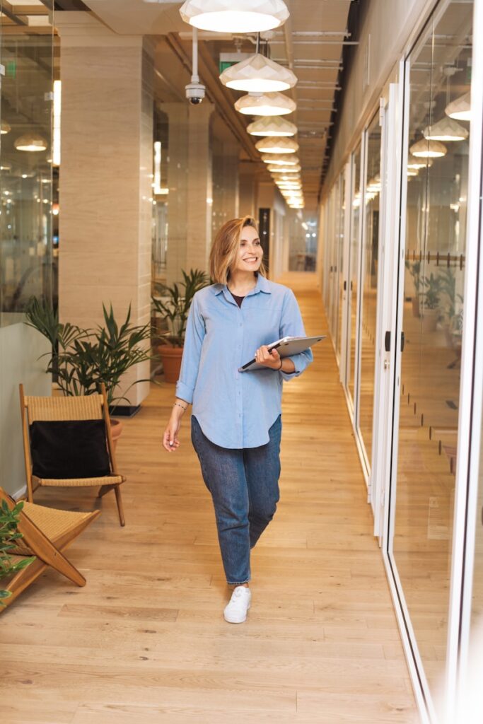 SupremeCall.com - Los Angeles - woman in blue dress shirt and blue denim jeans standing beside brown wooden chair