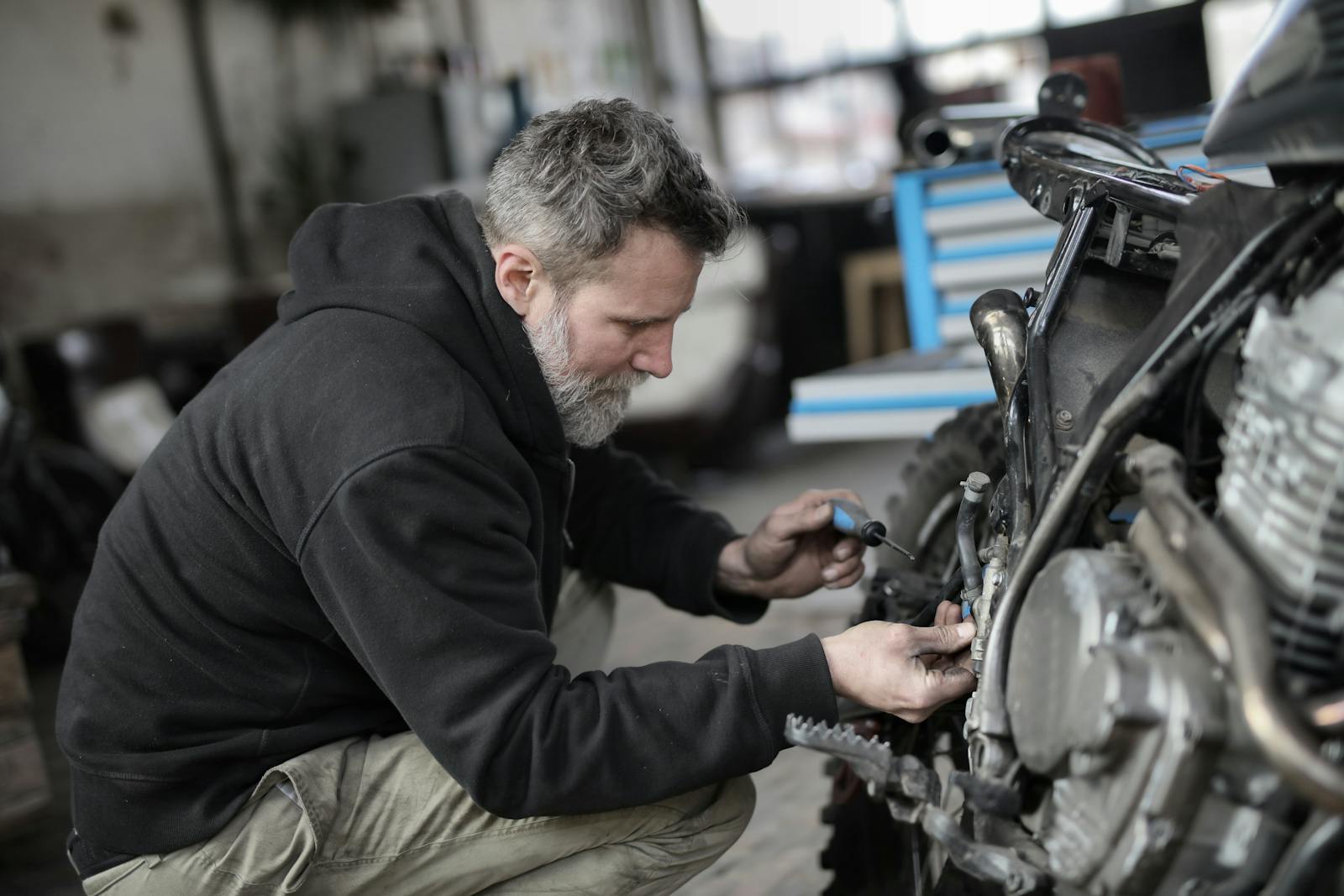 SupremeCall.com - Bearded man fixing motorcycle in workshop