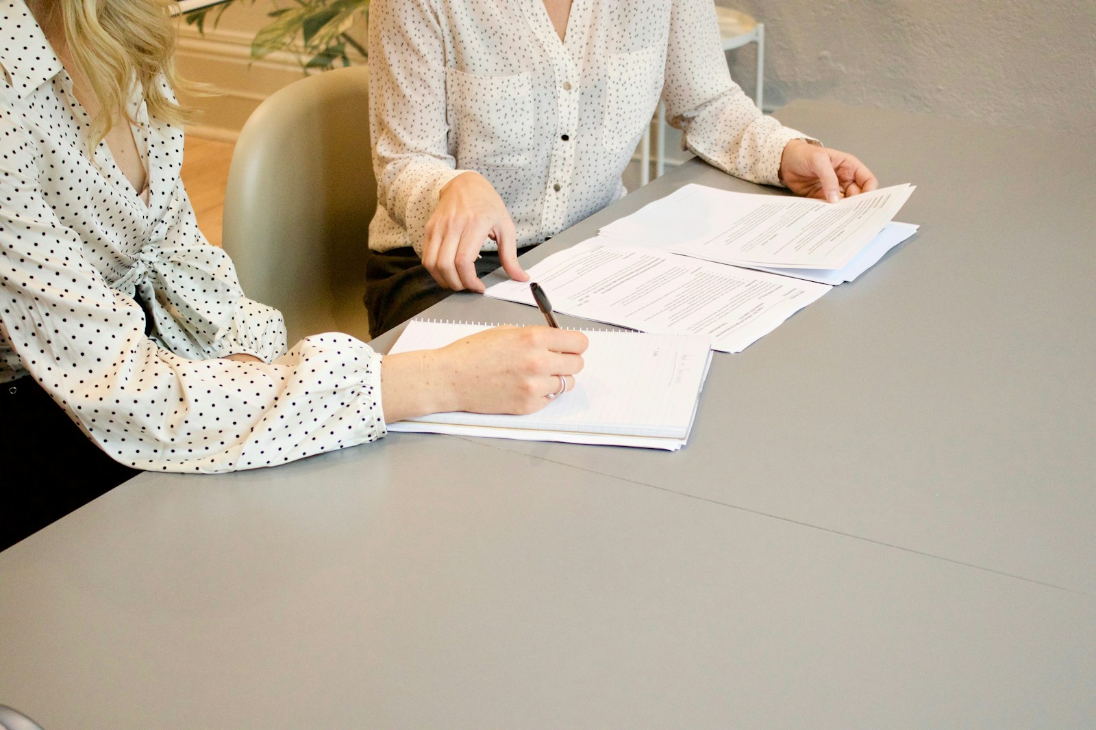 SupremeCall.com - woman signing on white printer paper beside woman about to touch the documents